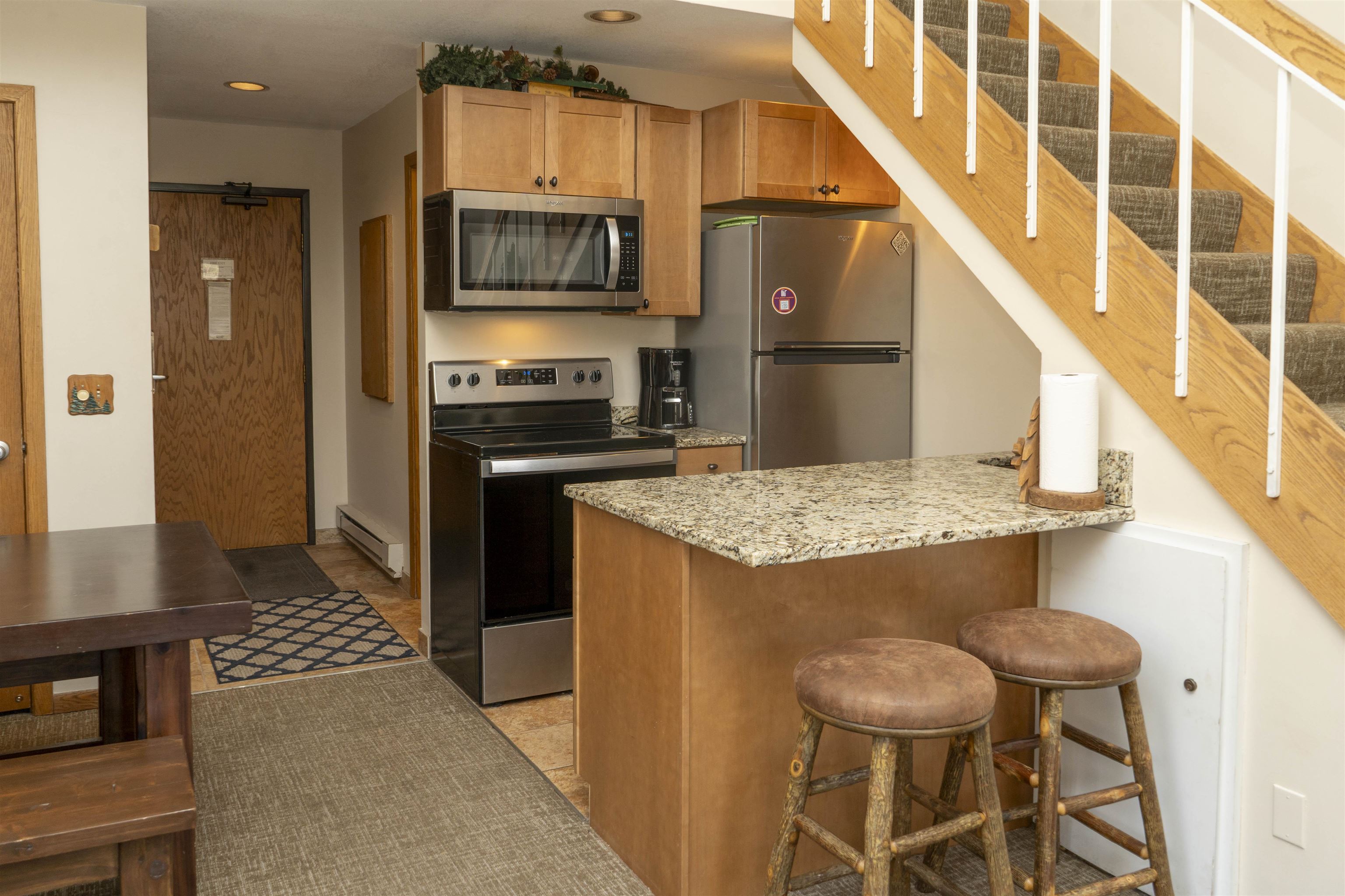 111 Bridge Run Lane, Unit 111 Lutsen, MN 55612 - Photo 7 of 48 Kitchen with appliances with stainless steel finishes, light stone countertops, a baseboard radiator, a kitchen bar, and a peninsula