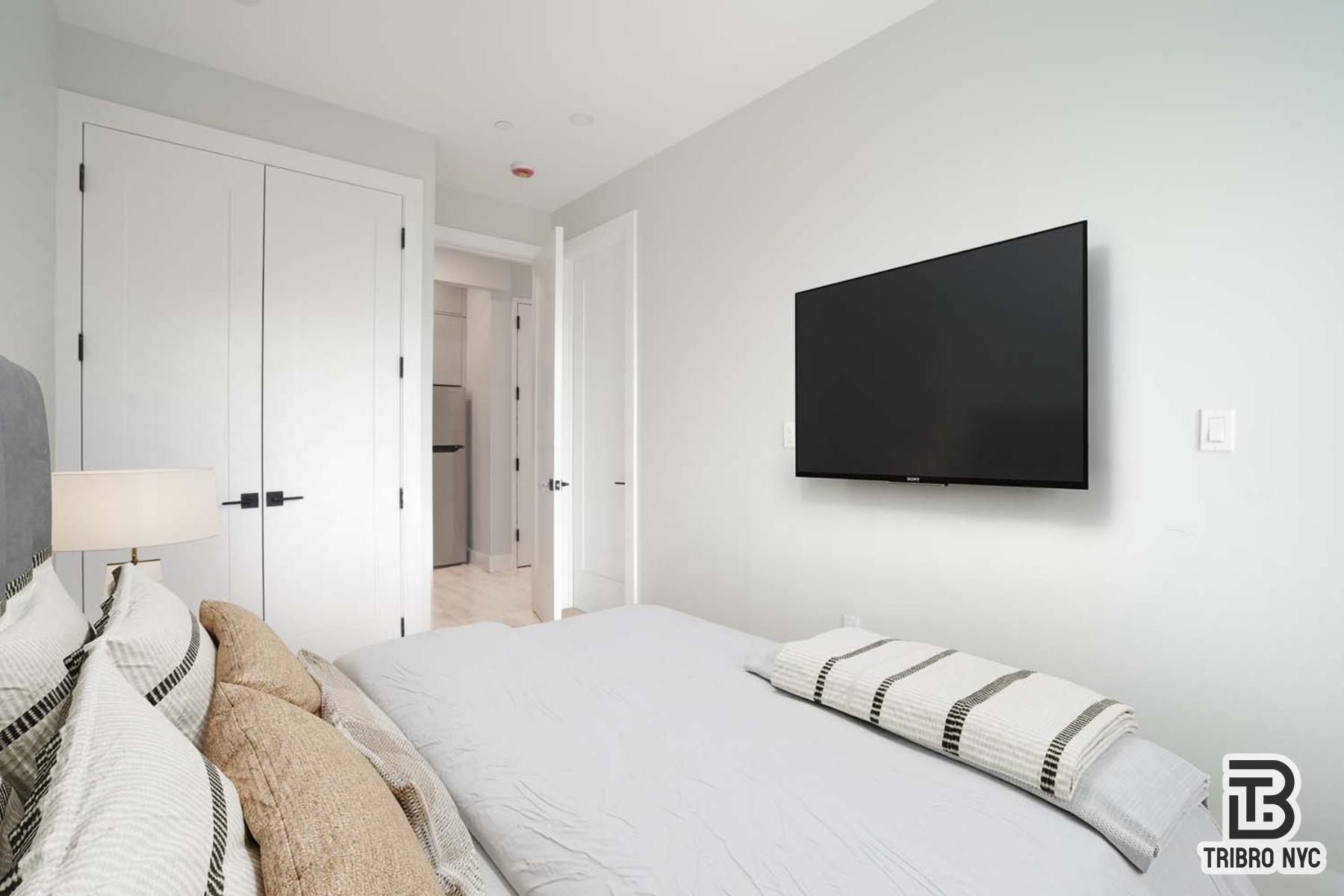 92 Manhattan Avenue, Unit 4X Brooklyn, NY 11206 - Photo 4 of 7 a bedroom with a bed and a flat screen tv