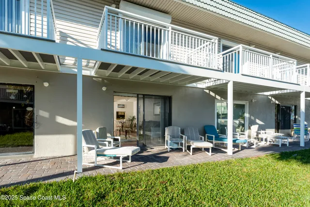 a view of a house with patio chairs and table