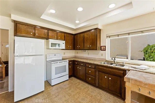 a kitchen with stainless steel appliances granite countertop a refrigerator a sink dishwasher a stove with wooden cabinets and floor