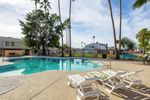 a view of a swimming pool with a yard and palm trees