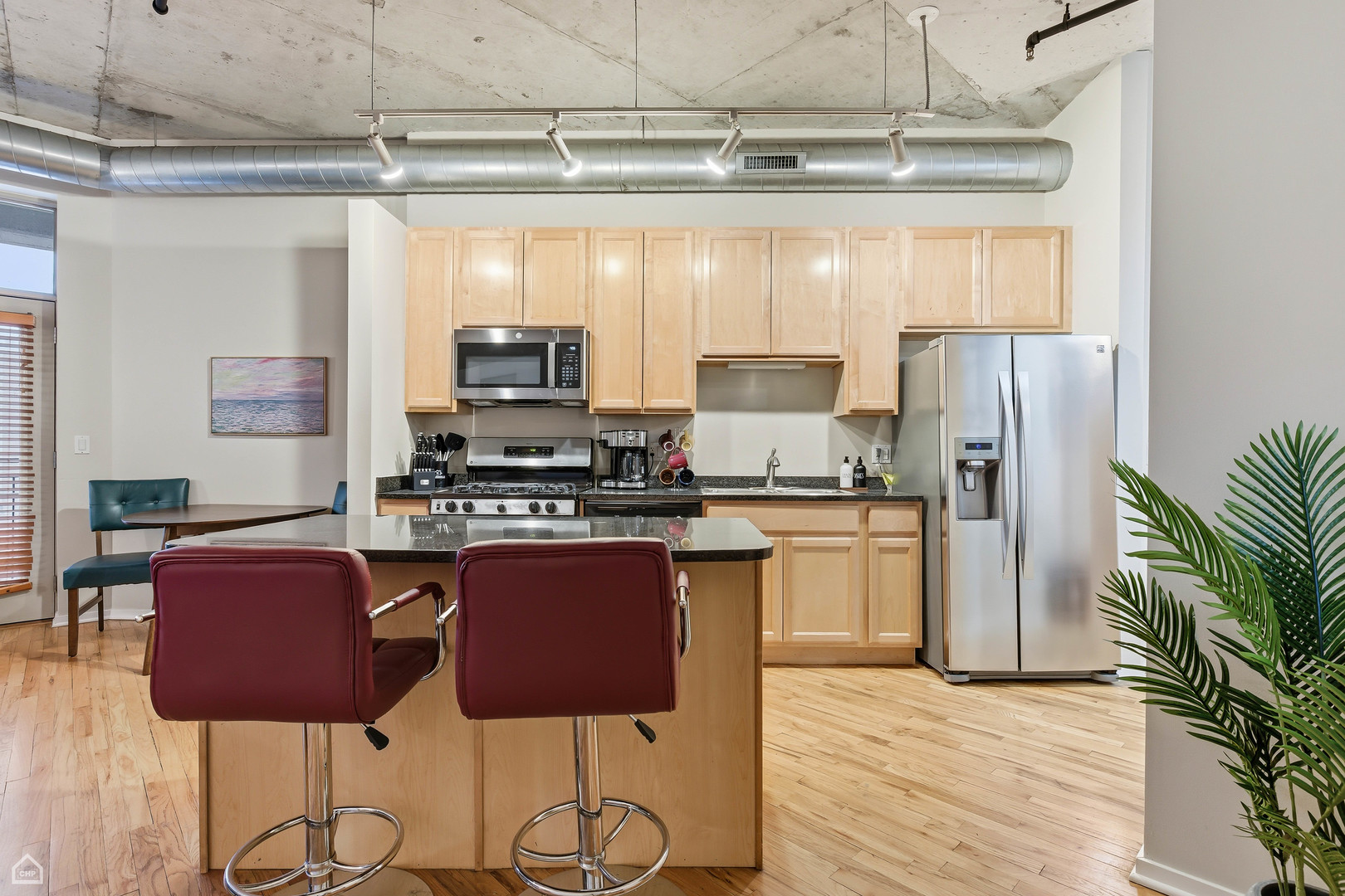 6 South Laflin Street, Unit 920 Chicago, IL 60607 - Photo 4 of 17 a kitchen with stainless steel appliances granite countertop a stove top oven a refrigerator and a dining table with wooden floor