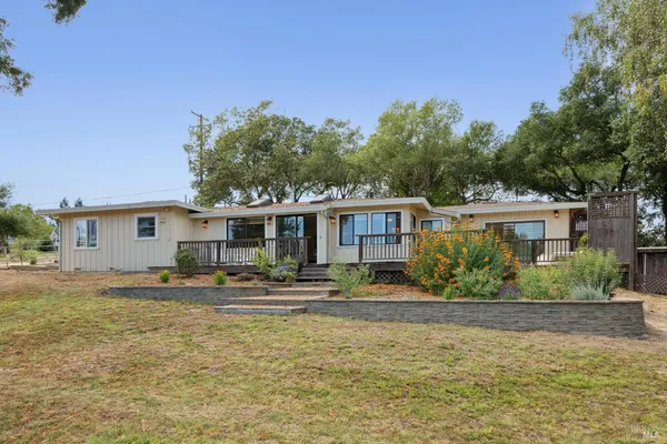 a front view of a house with a yard tree and outdoor seating