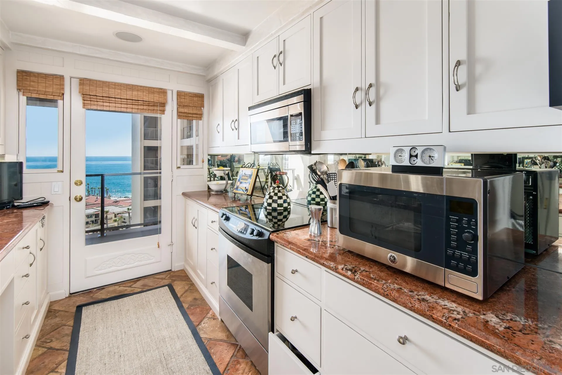 939 Coast Boulevard, Unit 16F La Jolla, CA 92037 - Photo 10 of 22 a kitchen with stainless steel appliances granite countertop a stove a microwave and a white cabinets