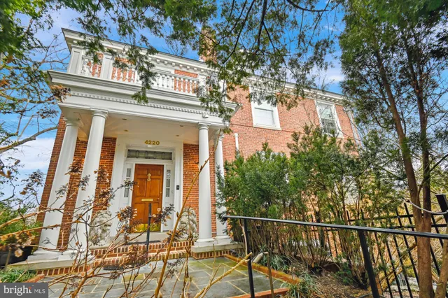 a view of a brick house with large windows and a tree