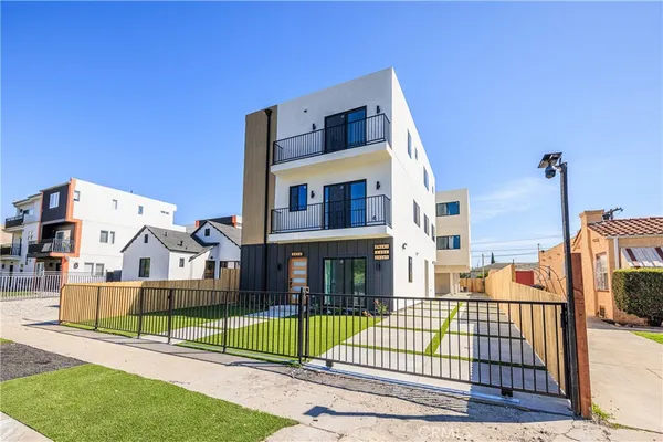 a view of a brick house with a small yard and large trees