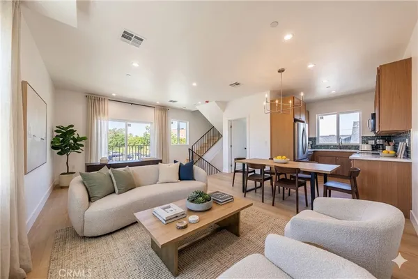 a living room with furniture kitchen view and a large window