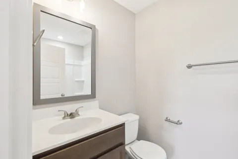 a bathroom with a granite countertop sink mirror and a toilet