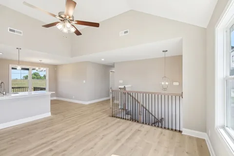 an empty room with wooden floor fan and windows