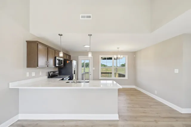a large white kitchen with a large window a sink and a chandelier
