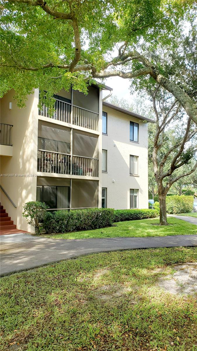 204 Foxtail Drive, Unit D1 Greenacres, FL 33415 - Photo 11 of 12 a view of a white house next to a yard with big trees