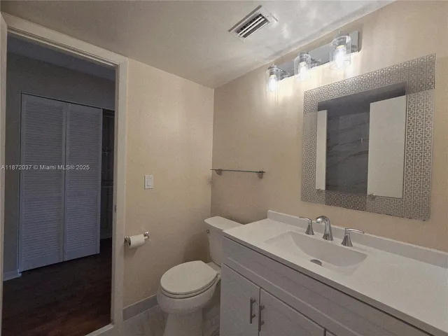 a bathroom with a granite countertop sink a toilet and a mirror