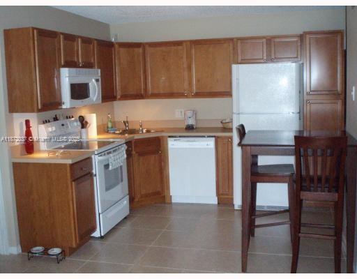 204 Foxtail Drive, Unit D1 Greenacres, FL 33415 - Photo 9 of 12 a kitchen with stainless steel appliances wooden cabinets and granite counter tops