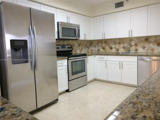a kitchen with granite countertop a refrigerator stove and microwave