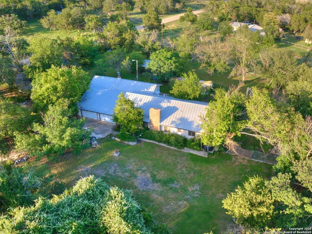 an aerial view of residential houses with outdoor space and trees