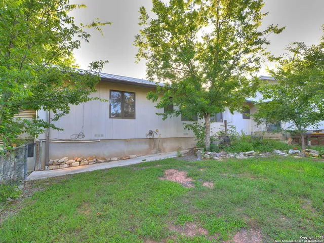 a view of a backyard with large trees and wooden fence