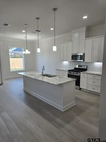 a kitchen with stainless steel appliances granite countertop a sink a stove and a refrigerator