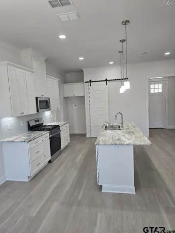 a large kitchen with granite countertop a sink stainless steel appliances and cabinets