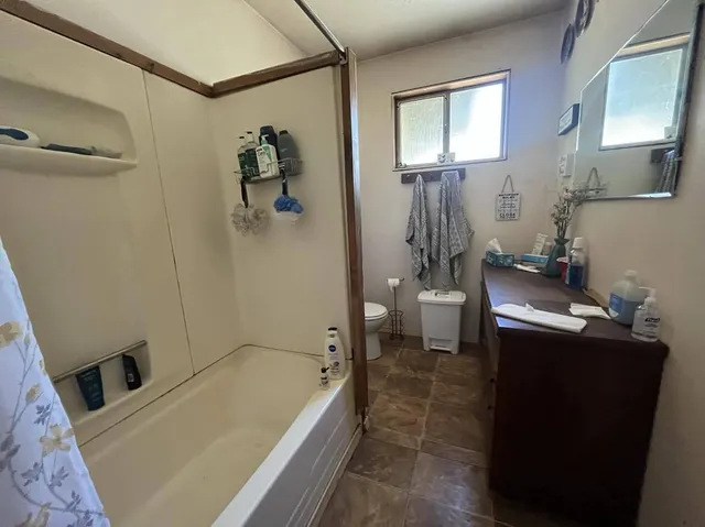 a bathroom with a granite countertop sink a toilet and shower