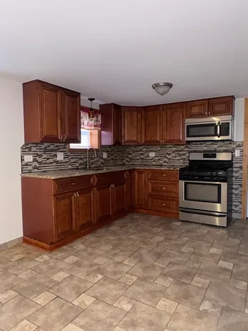 a kitchen with stainless steel appliances granite countertop a stove a sink and a refrigerator