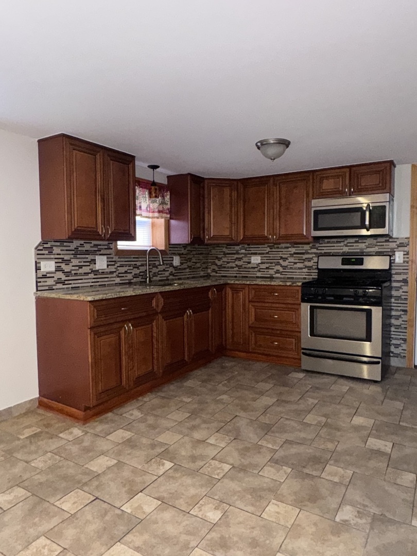12255 South McDaniels Street, Unit GN Alsip, IL 60803 - Photo 5 of 11 a kitchen with stainless steel appliances granite countertop a stove a sink and a refrigerator