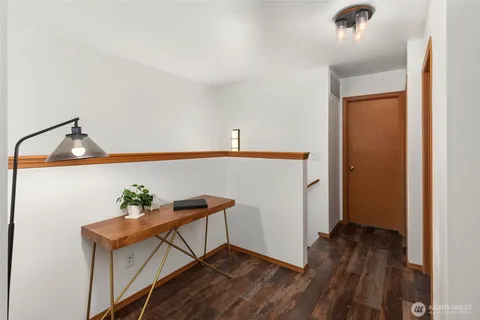 a view of a hallway to room with wooden floor and fan