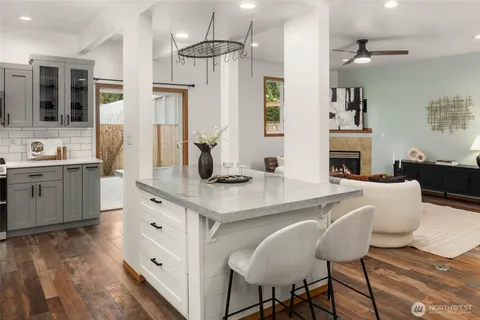 a kitchen with stainless steel appliances kitchen island granite countertop a table chairs in it and wooden floors