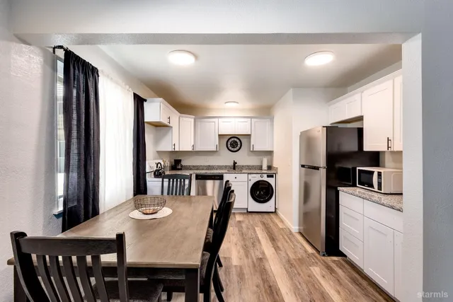 a kitchen with stainless steel appliances granite countertop a dining table chairs refrigerator sink and cabinets