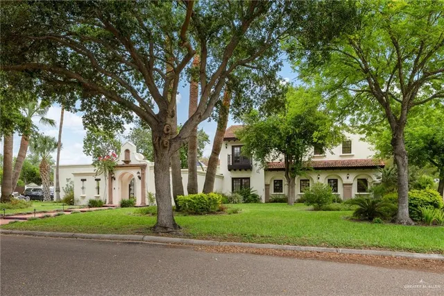 front view of a brick house with a yard and large trees