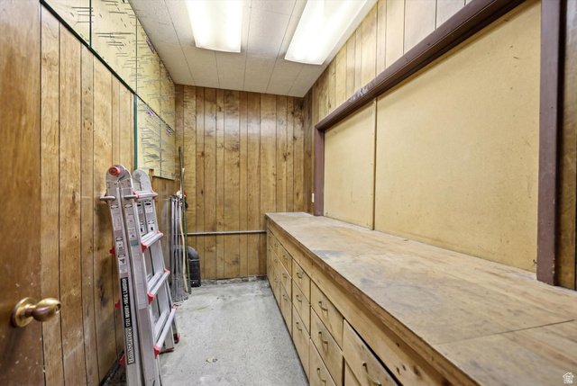 292 West 400 South Springville, UT 84663 - Photo 36 of 37 Utility room featuring wood paneling, extensive built-in cabinetry, a large workbench surface, and overhead fluorescent lighting