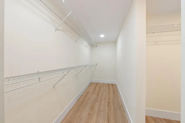 a kitchen with white cabinets and wooden floor