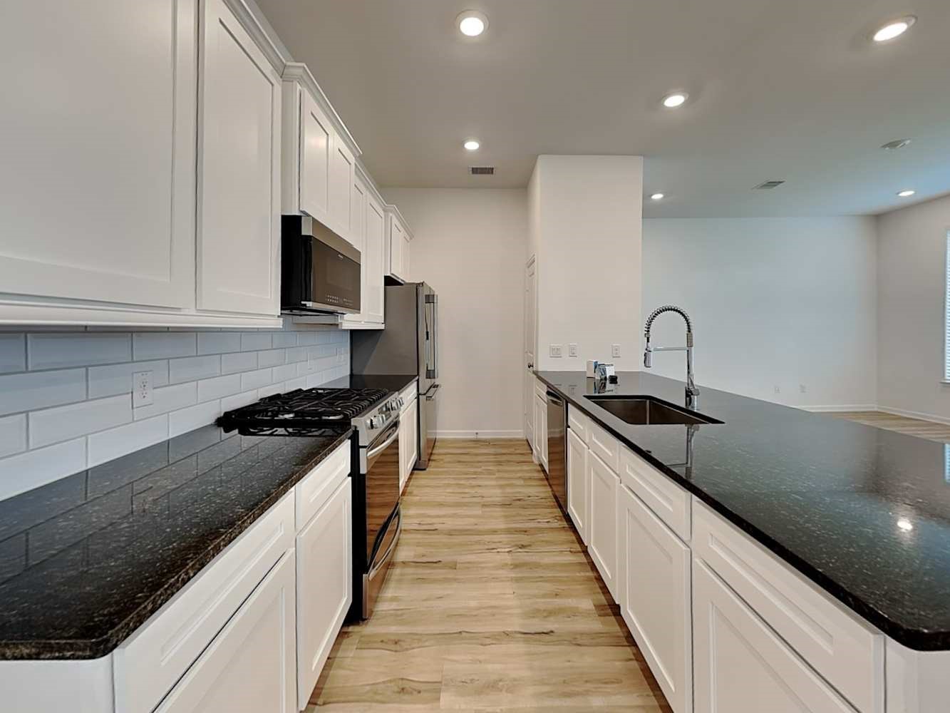 4023 Champlain Way Rosharon, TX 77583 - Photo 7 of 14 a large kitchen with stainless steel appliances granite countertop a sink a stove and a wooden floors