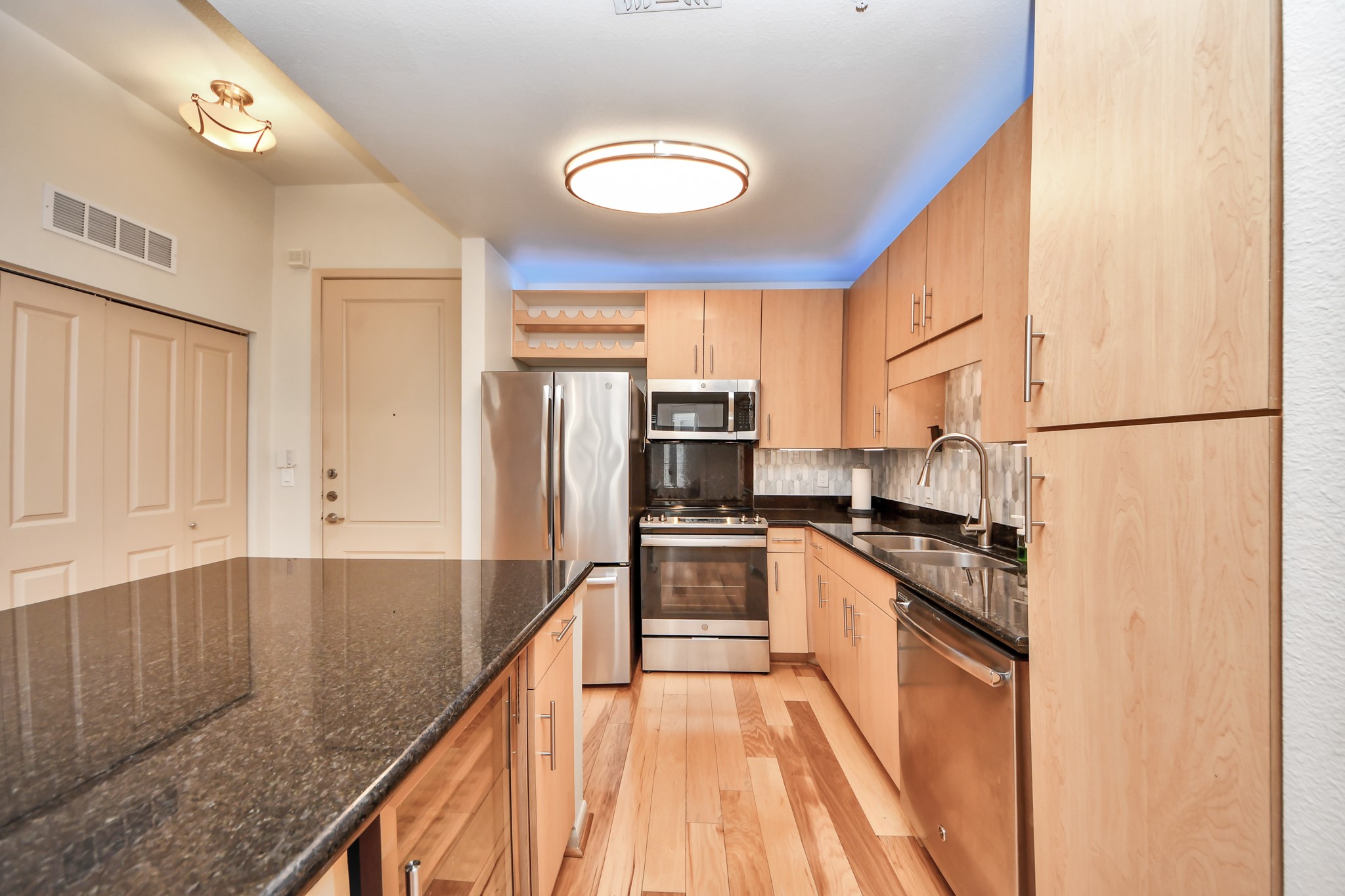 3505 Sage Road, Unit 604 Houston, TX 77056 - Photo 8 of 40 a kitchen with stainless steel appliances granite countertop a refrigerator a stove and a sink with wooden floor