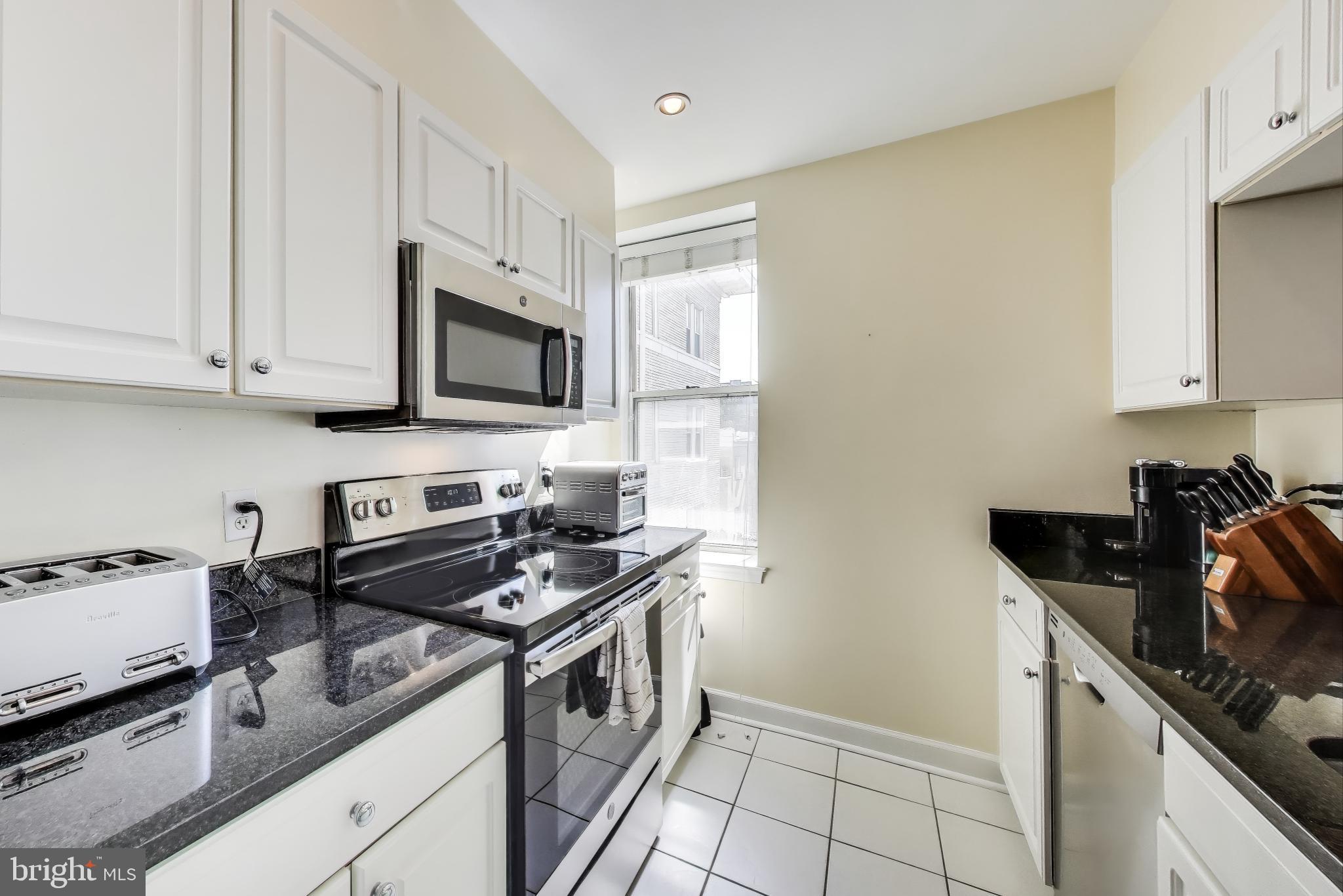 1619 R Street Northwest, Unit 501 Washington, DC 20009 - Photo 14 of 25 a kitchen with granite countertop a stove a sink and a white cabinets
