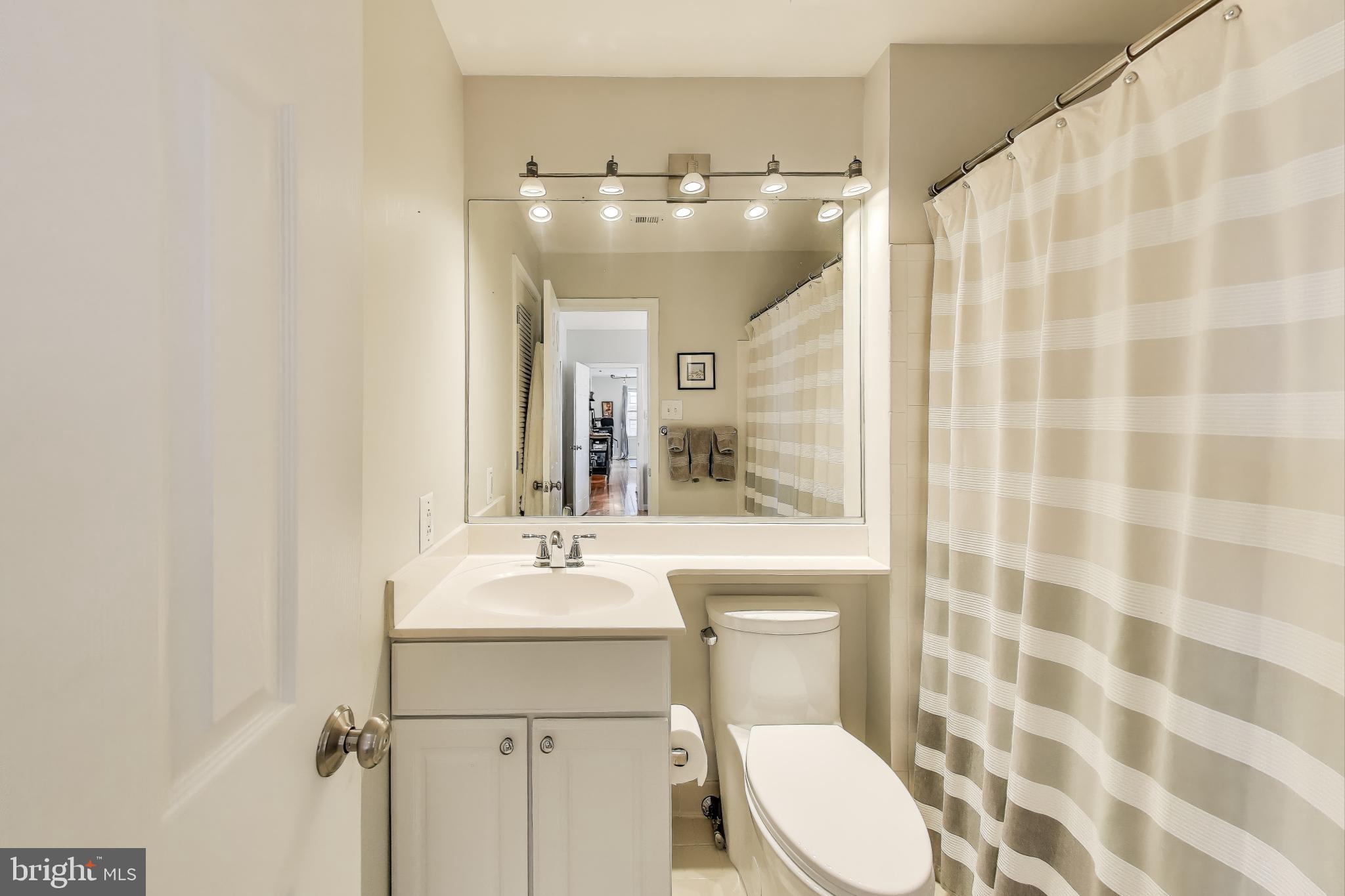 1619 R Street Northwest, Unit 501 Washington, DC 20009 - Photo 19 of 25 a bathroom with a sink a toilet a mirror and shower curtain