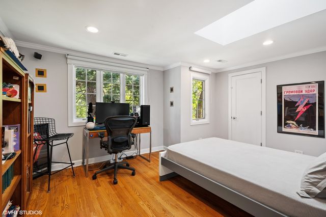 a bedroom with a bed a desk and chair with wooden floor