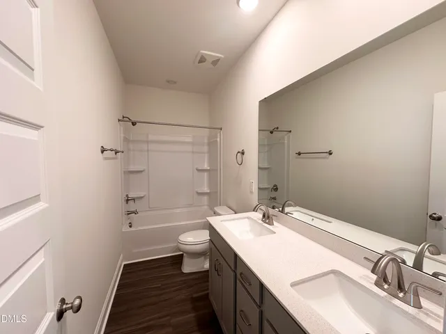 a bathroom with a granite countertop sink toilet a large mirror a shower and a bathtub