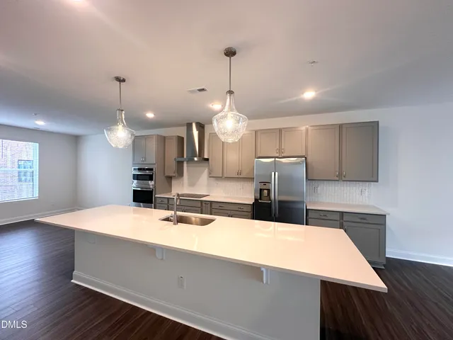 a large kitchen with stainless steel appliances a large counter top a refrigerator and a sink