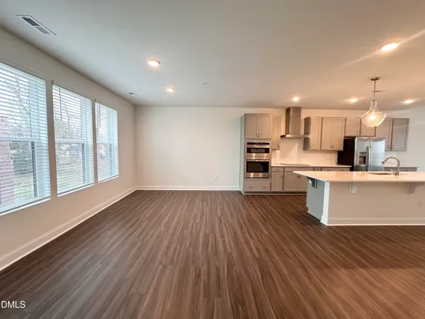 a view of kitchen with kitchen island wooden floors and stainless steel appliances