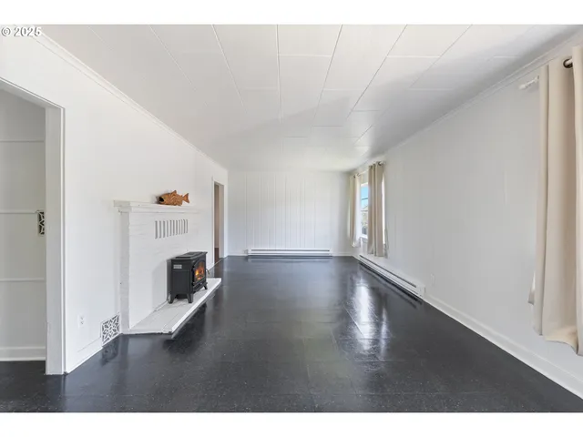 a view of empty room with fireplace and wooden floor
