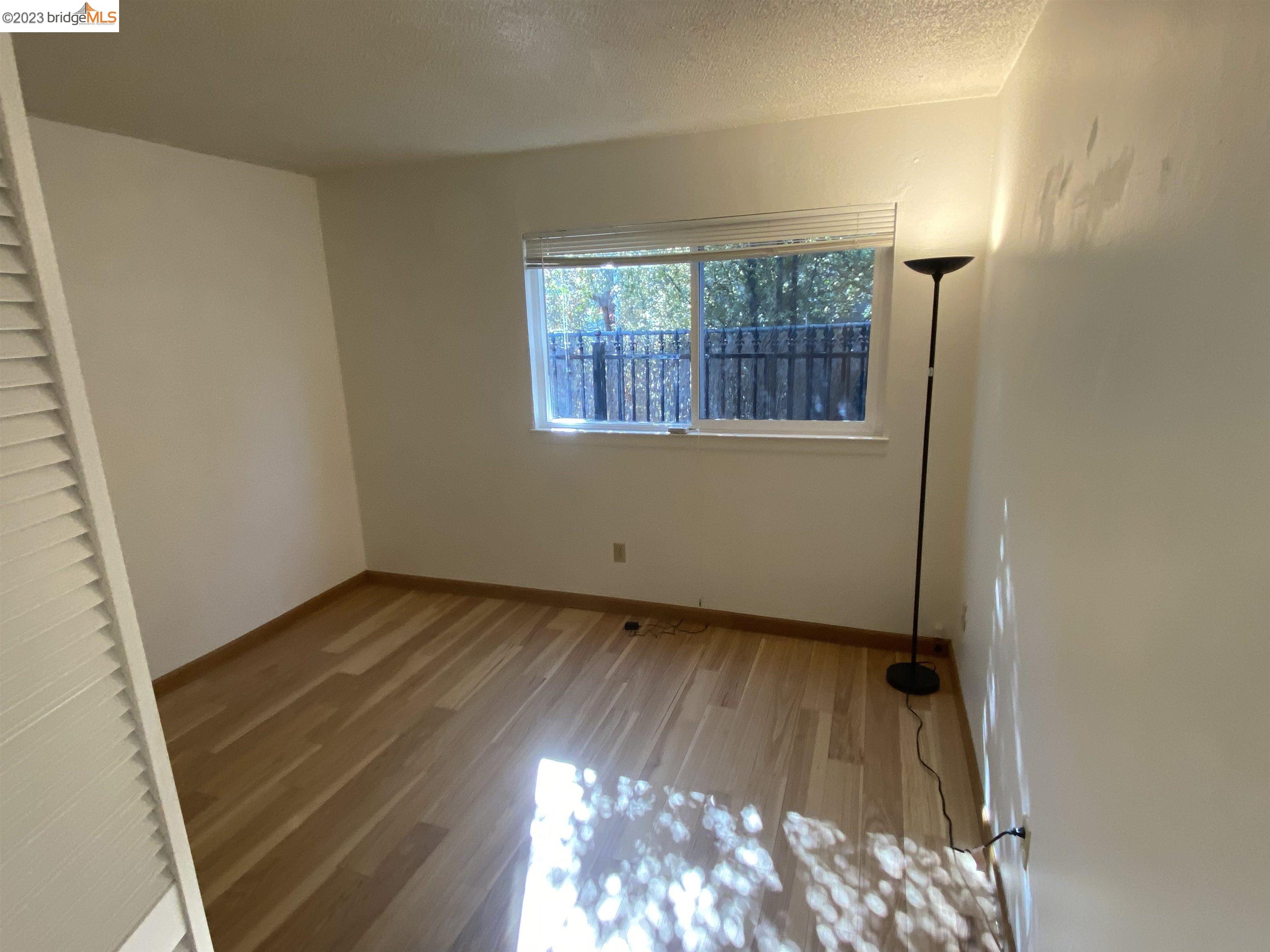 968 45th Street, Unit A Oakland, CA 94608 - Photo 13 of 16 an empty room with wooden floor and windows