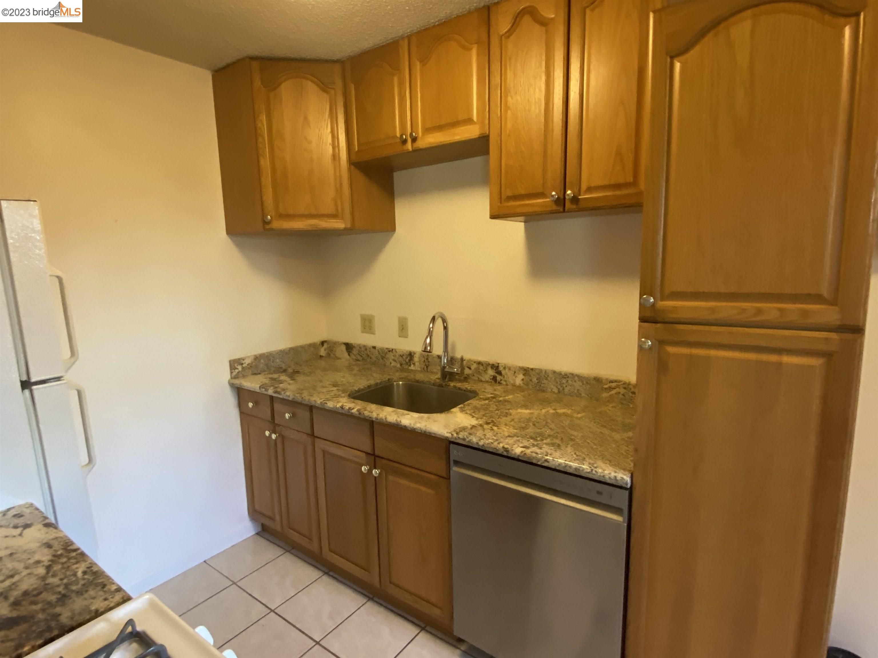 968 45th Street, Unit A Oakland, CA 94608 - Photo 7 of 16 a kitchen with stainless steel appliances granite countertop a refrigerator and a stove
