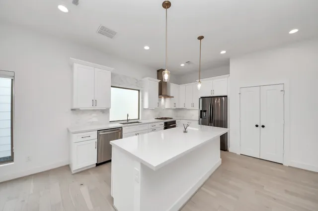 a large white kitchen with a white countertops a stove a sink and a refrigerator