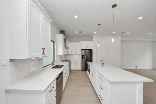 a large white kitchen with a large window a sink and stainless steel appliances