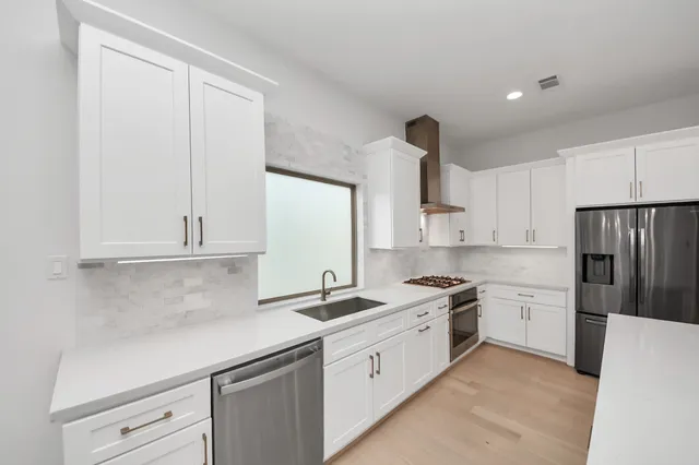 a kitchen with white cabinets and stainless steel appliances