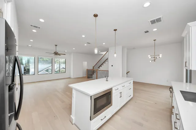a large room with a large kitchen island wooden floor and a ceiling fan