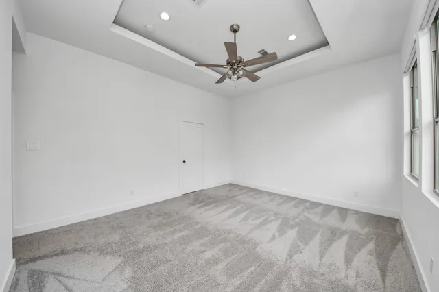 an empty room with a chandelier fan and windows