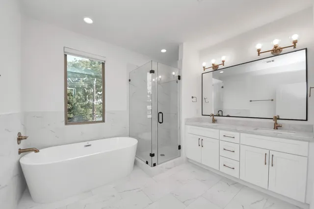a bathroom with a tub sink double vanity granite tub shower and a mirror