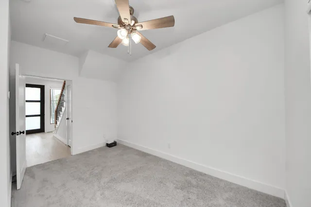 an empty room with a chandelier fan and windows