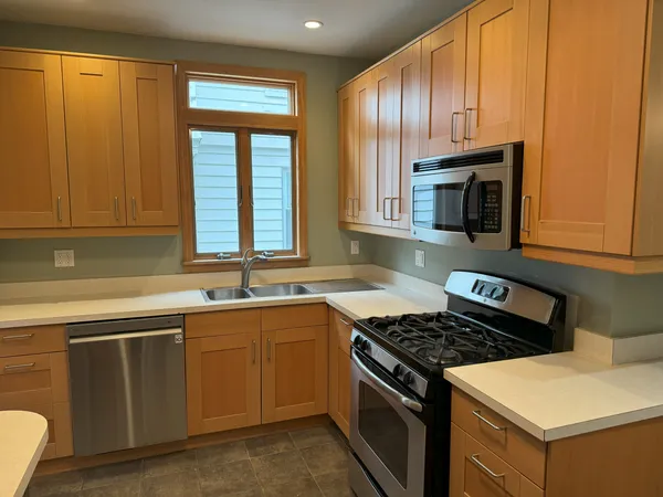 a kitchen with granite countertop stainless steel appliances a sink stove and cabinets